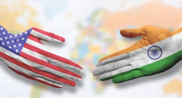 Hands painted with Indian and American flags shaking hands.